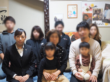 ご自宅に今でも飾られているパネルの前で(後列左から2番目がご長女様、前列左端が担当した中尾さん)